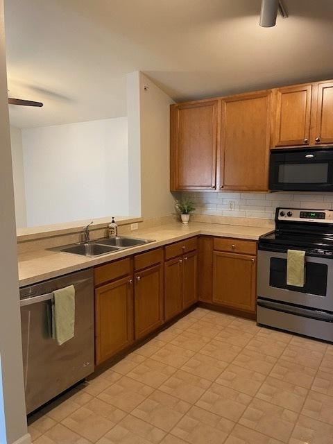 kitchen with appliances with stainless steel finishes, backsplash, ceiling fan, and sink