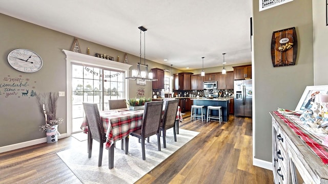 dining space featuring dark wood-type flooring, a wealth of natural light, and an inviting chandelier