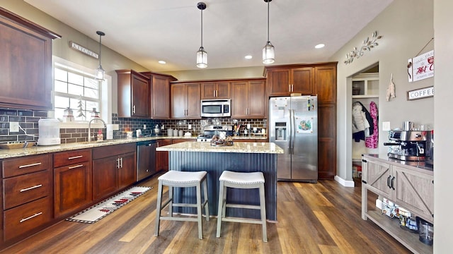 kitchen with hanging light fixtures, a center island, sink, and appliances with stainless steel finishes