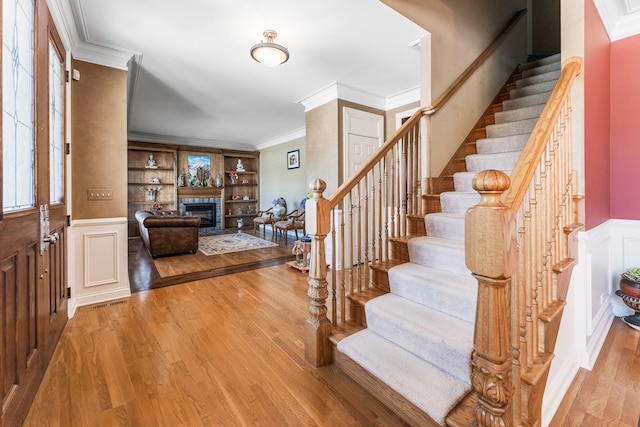 foyer featuring light hardwood / wood-style floors, a wealth of natural light, and crown molding