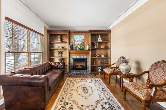 living area featuring hardwood / wood-style flooring, built in features, ornamental molding, and a fireplace