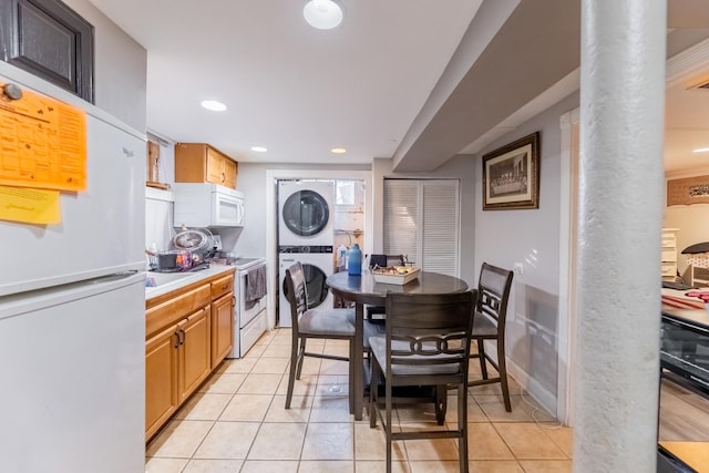 kitchen with light tile patterned floors, white appliances, decorative columns, and stacked washer and clothes dryer