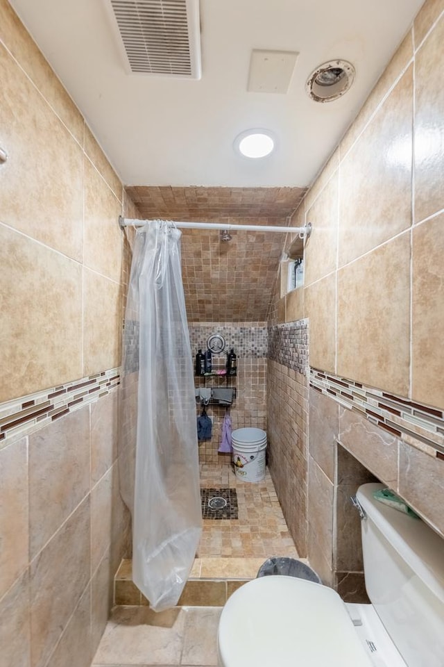 bathroom featuring toilet, tile walls, and a shower with shower curtain