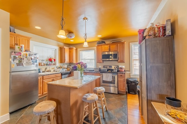 kitchen featuring a center island, sink, stainless steel appliances, a kitchen breakfast bar, and decorative light fixtures