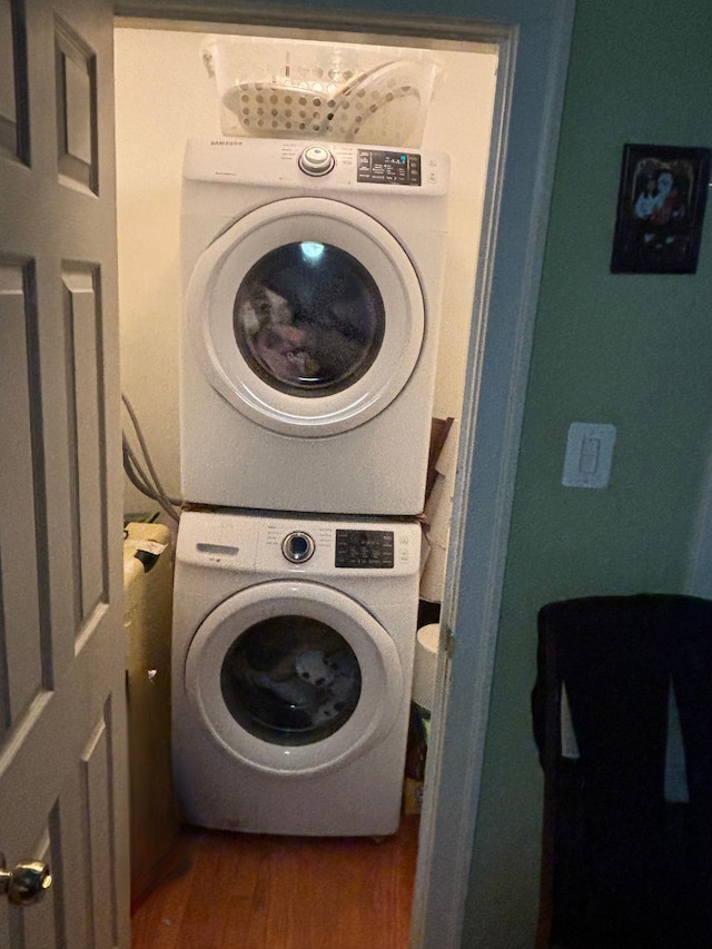 laundry area with stacked washer and dryer and dark wood-type flooring