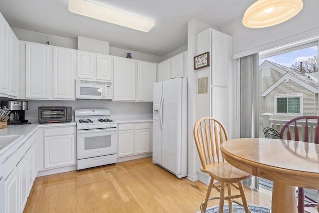 kitchen with white cabinets, white appliances, and light hardwood / wood-style flooring