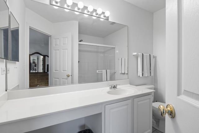 bathroom featuring vanity, toilet, and a shower with door