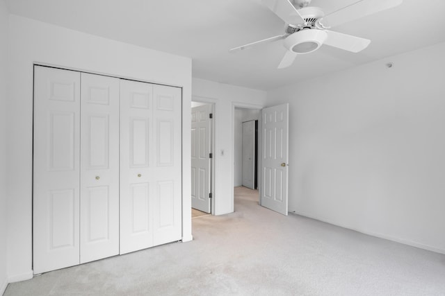 unfurnished bedroom featuring ceiling fan, a closet, and light colored carpet