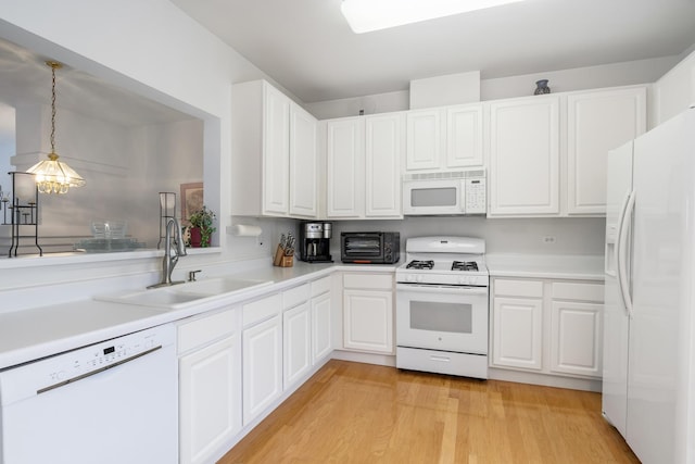 kitchen featuring white appliances, decorative light fixtures, white cabinetry, and sink