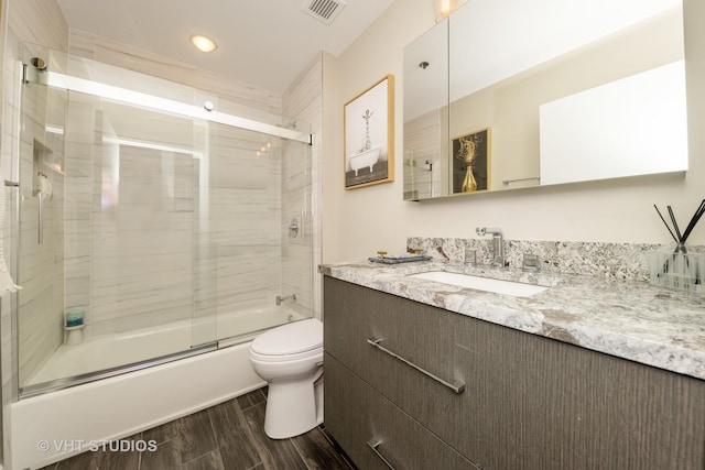 full bathroom featuring toilet, bath / shower combo with glass door, and vanity