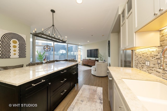 kitchen featuring an inviting chandelier, white cabinetry, dark hardwood / wood-style flooring, light stone countertops, and sink