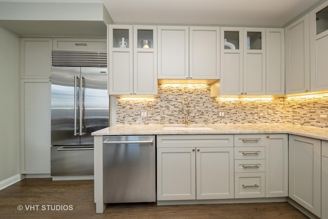 kitchen with white cabinets, appliances with stainless steel finishes, sink, and light stone counters