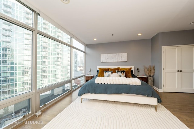 bedroom featuring wood-type flooring, multiple windows, and a wall of windows