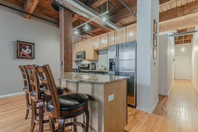 kitchen featuring beam ceiling, dark stone countertops, appliances with stainless steel finishes, wood ceiling, and light wood-type flooring