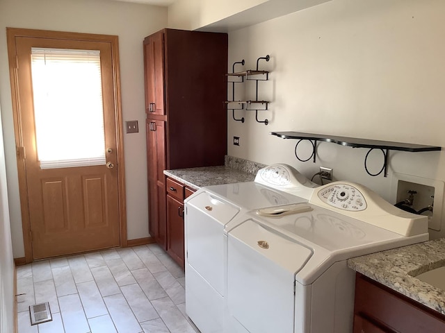 laundry area featuring separate washer and dryer, a wealth of natural light, and cabinets