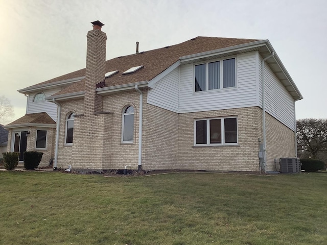 back of property featuring central air condition unit and a yard