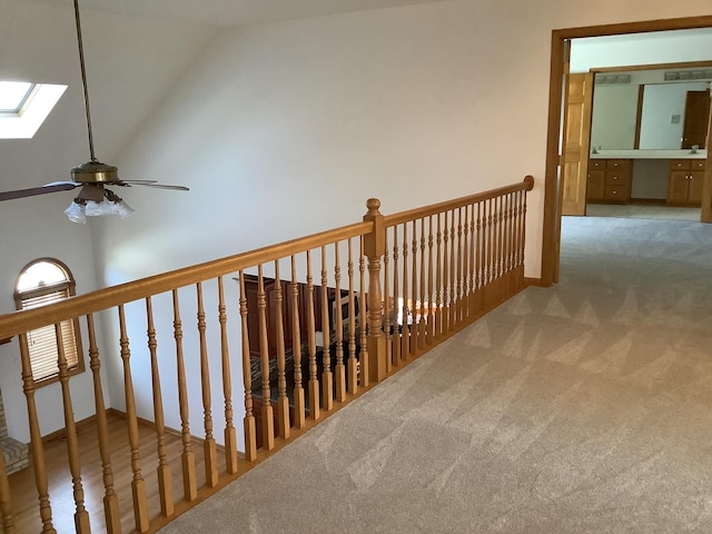 corridor with carpet floors and vaulted ceiling with skylight