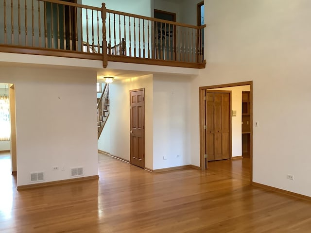 empty room with a towering ceiling and light hardwood / wood-style flooring