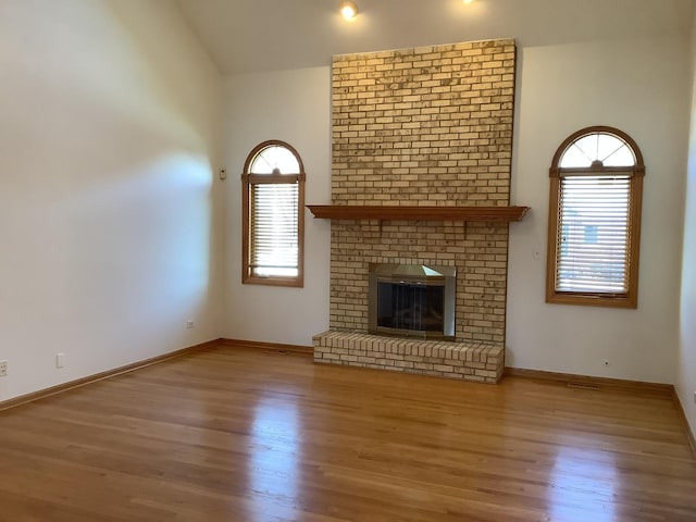 unfurnished living room with a fireplace, light hardwood / wood-style floors, and lofted ceiling