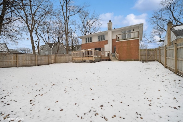 snow covered back of property with a deck