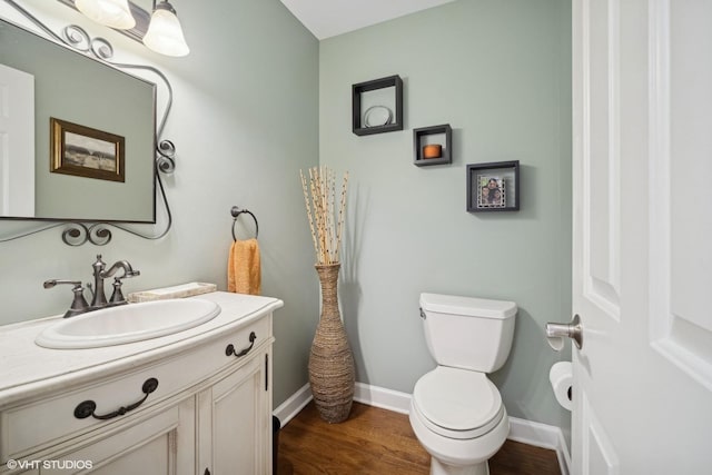 bathroom with toilet, vanity, and hardwood / wood-style floors