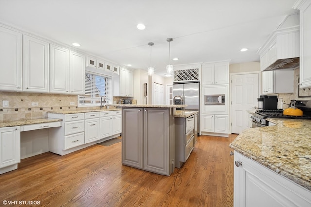 kitchen featuring white cabinetry, pendant lighting, and built in appliances