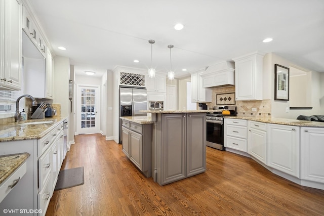 kitchen with white cabinetry, appliances with stainless steel finishes, custom exhaust hood, and hanging light fixtures