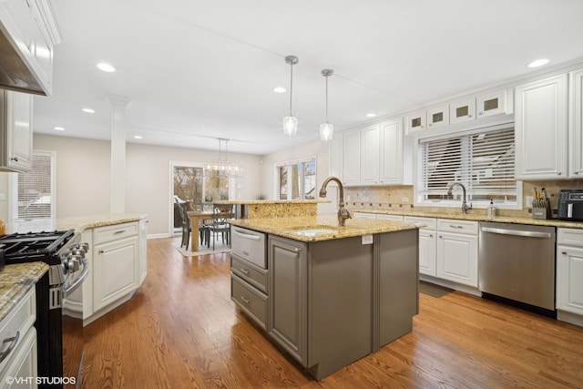 kitchen featuring an island with sink, appliances with stainless steel finishes, decorative backsplash, pendant lighting, and white cabinets