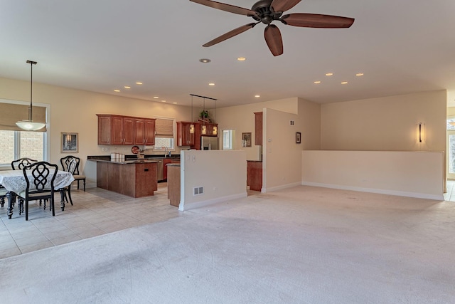 kitchen featuring light carpet, a center island, ceiling fan, and decorative light fixtures