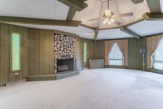 unfurnished living room featuring beam ceiling, ceiling fan, a baseboard radiator, a stone fireplace, and a textured ceiling