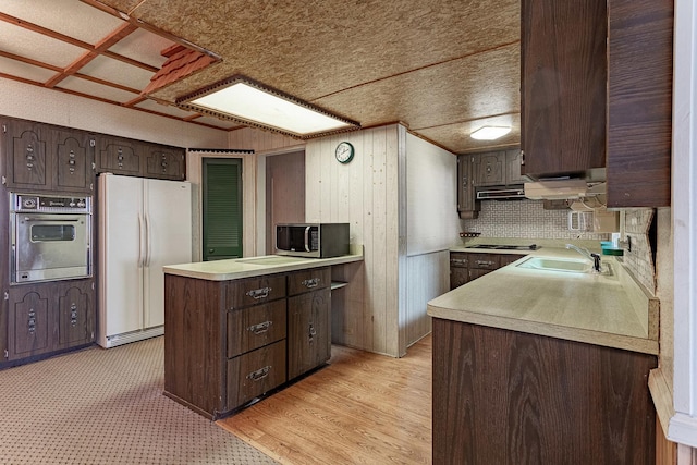 kitchen featuring sink, dark brown cabinetry, light wood-type flooring, appliances with stainless steel finishes, and kitchen peninsula