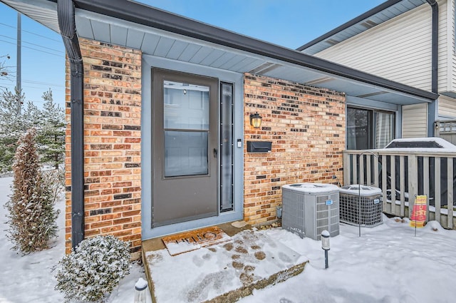 snow covered property entrance featuring central AC