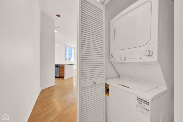 clothes washing area with stacked washer and dryer and light hardwood / wood-style flooring