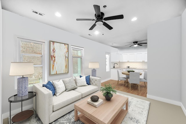 living room featuring ceiling fan, light hardwood / wood-style floors, and sink