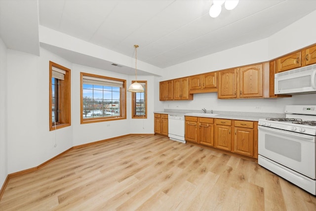 kitchen with sink, decorative light fixtures, white appliances, and light hardwood / wood-style flooring