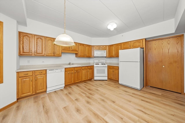 kitchen featuring white appliances, decorative light fixtures, light hardwood / wood-style flooring, and sink