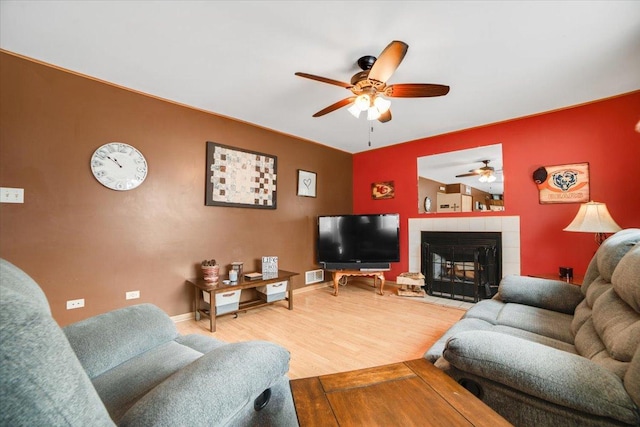 living room with ceiling fan, hardwood / wood-style floors, and a tile fireplace