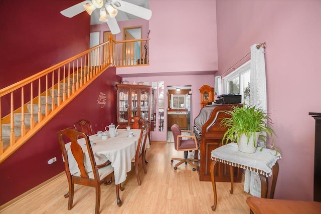 dining space featuring light hardwood / wood-style floors, ceiling fan, and a high ceiling