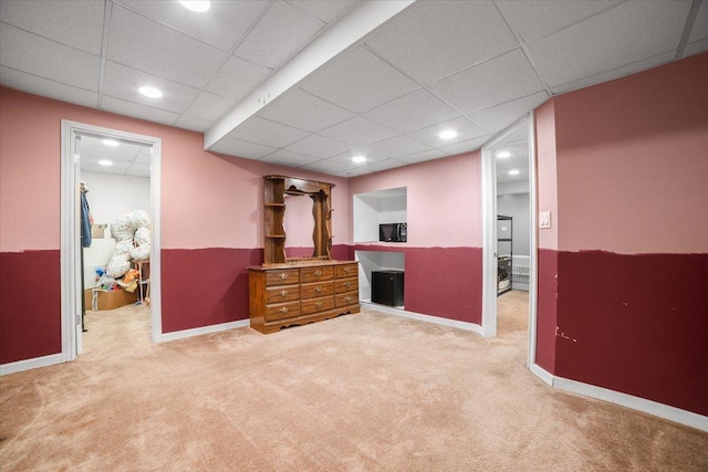 interior space with a paneled ceiling and light carpet