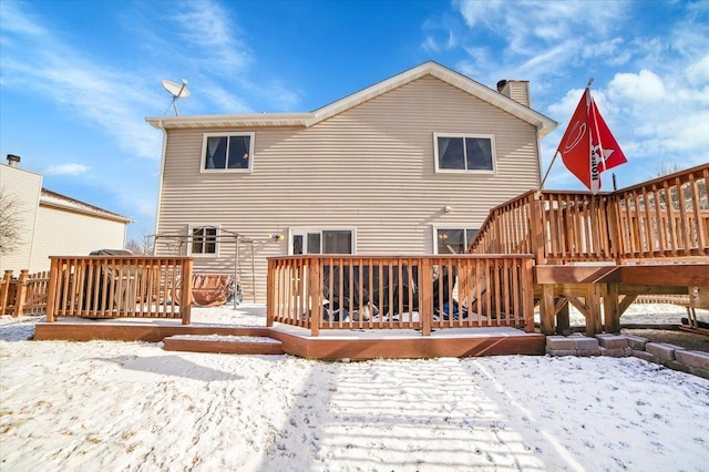 snow covered back of property with a deck