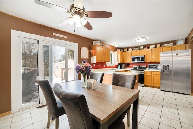 tiled dining space with ceiling fan and sink