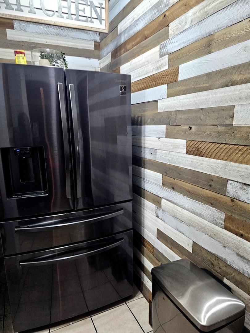 details with stainless steel refrigerator with ice dispenser and wooden walls