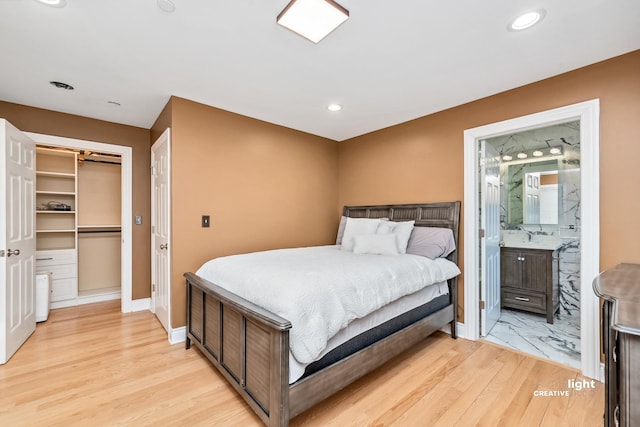 bedroom featuring a walk in closet, connected bathroom, light hardwood / wood-style floors, and a closet