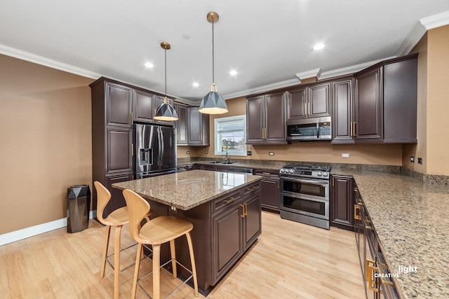 kitchen with a breakfast bar, hanging light fixtures, a center island, dark brown cabinetry, and stainless steel appliances