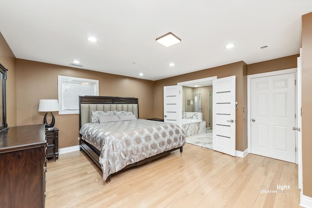 bedroom with ensuite bath and light wood-type flooring