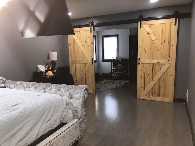 bedroom with dark hardwood / wood-style flooring and a barn door