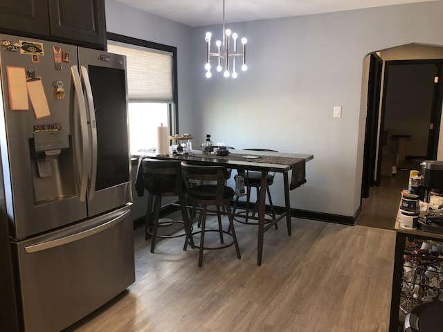 dining area featuring wood-type flooring and a notable chandelier