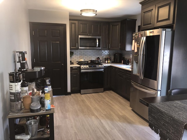 kitchen with backsplash, dark brown cabinets, light wood-type flooring, and stainless steel appliances