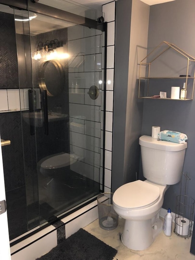 bathroom featuring toilet and a shower with shower door