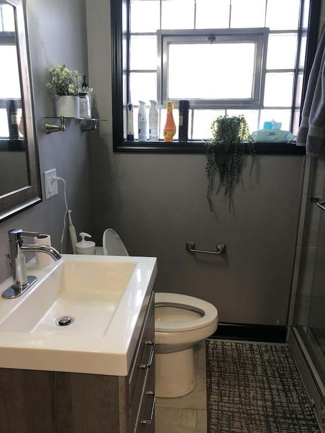 bathroom featuring tile patterned flooring, vanity, toilet, and a shower with shower door